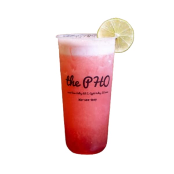 A pink and red layered drink from The PHO with a lime slice on a white background.
