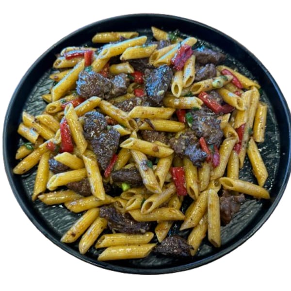 Penne pasta with beef, red bell peppers, and green onions on a black plate.