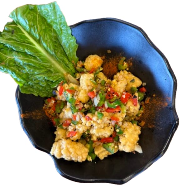 Vietnamese fried tofu with red and green peppers, onions, and spices, served with lettuce.