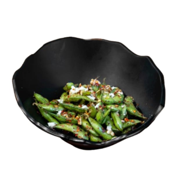 A black bowl filled with green edamame pods, topped with white flakes and red chili pepper.